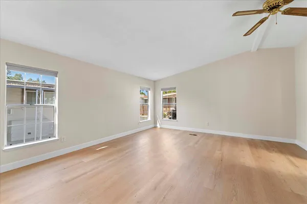 a view of an empty room with a window and wooden floor