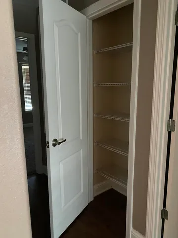 a view of an empty room with wooden floor and cabinets