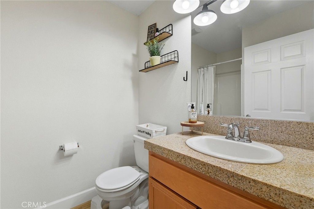 21711 Doss Place Saugus, CA 91350 - Photo 17 of 27 a bathroom with a granite countertop sink a toilet and a mirror