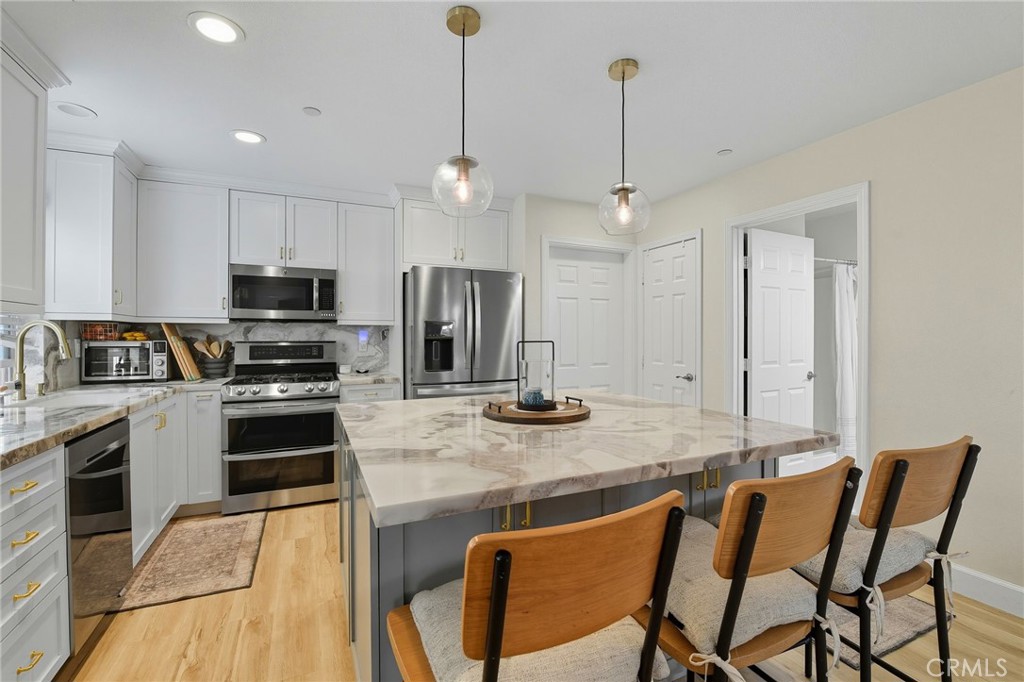 21711 Doss Place Saugus, CA 91350 - Photo 2 of 27 a kitchen with stainless steel appliances granite countertop a stove top oven a refrigerator a sink and chairs