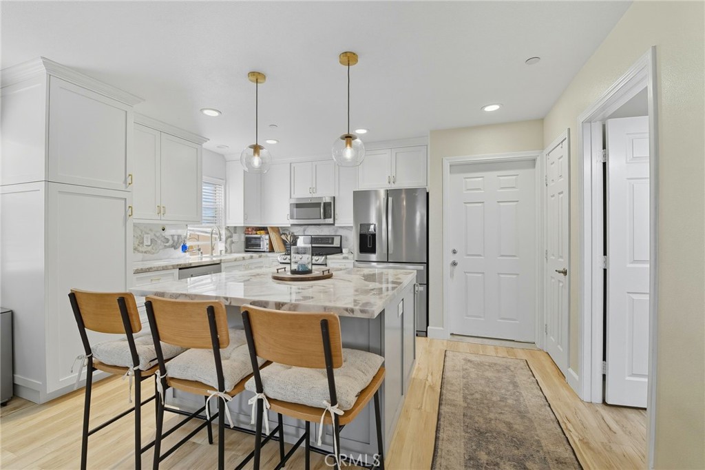 21711 Doss Place Saugus, CA 91350 - Photo 3 of 27 a kitchen with stainless steel appliances kitchen island granite countertop a dining table chairs and white cabinets