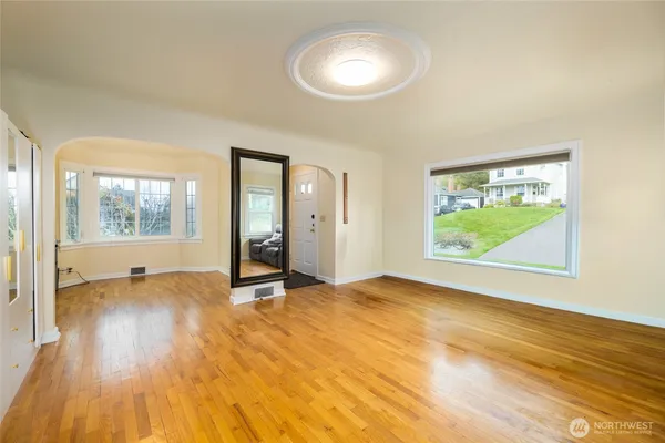 a view of an empty room with a window and wooden floor