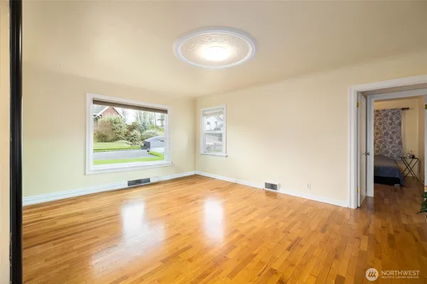 a view of an empty room with wooden floor and a window