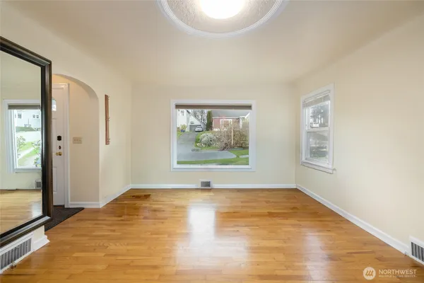 a view of an empty room with wooden floor and a window