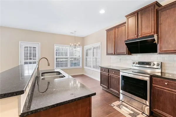 a kitchen with stainless steel appliances granite countertop a stove a sink and a microwave