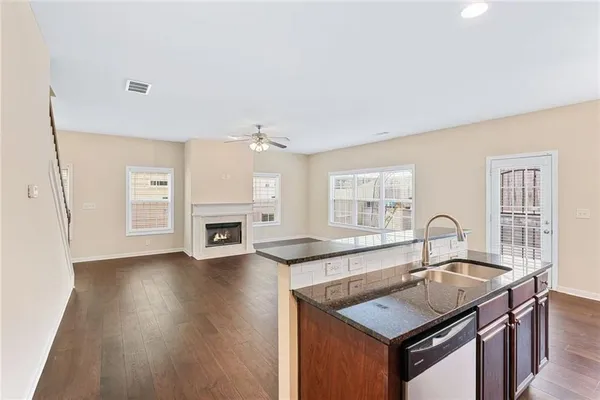 a kitchen with granite countertop a sink cabinets and wooden floor