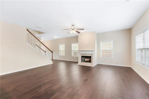 a view of an empty room with wooden floor fireplace and a window