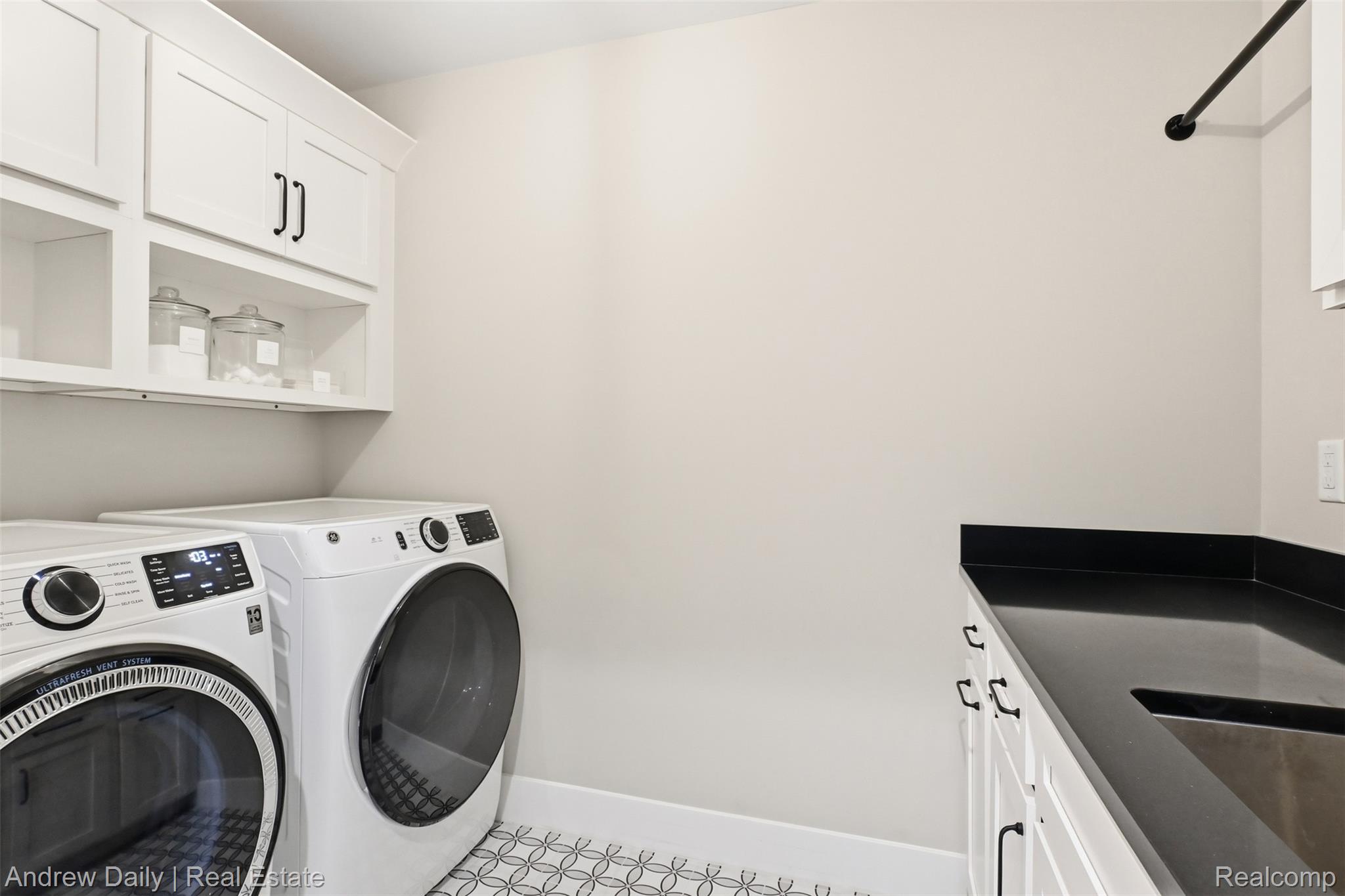 4661 Spears Road Pinckney, MI 48169 - Photo 29 of 56 Laundry area featuring white cabinetry with black hardware, open shelving, dark countertop, and decorative floor tile