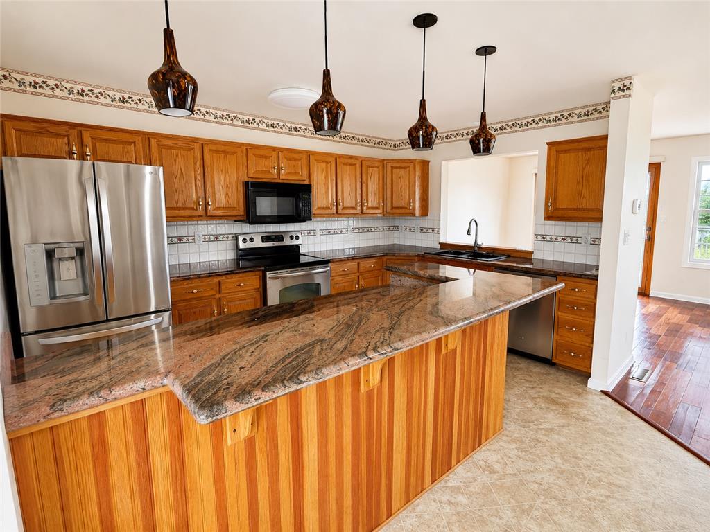 511 Howertown Road Northampton, PA 18067 - Photo 7 of 34 An inviting kitchen features a central island with natural wood paneling and richly veined stone countertops, ideal for casual dining.