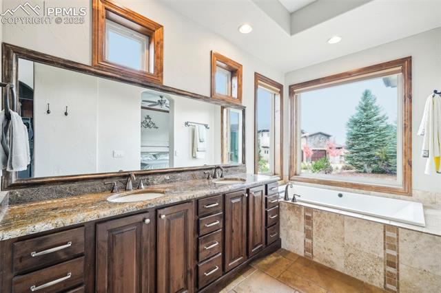 13665 Random Ridge View Colorado Springs, CO 80921 - Photo 24 of 49 Bathroom featuring vanity, tiled tub, and ceiling fan