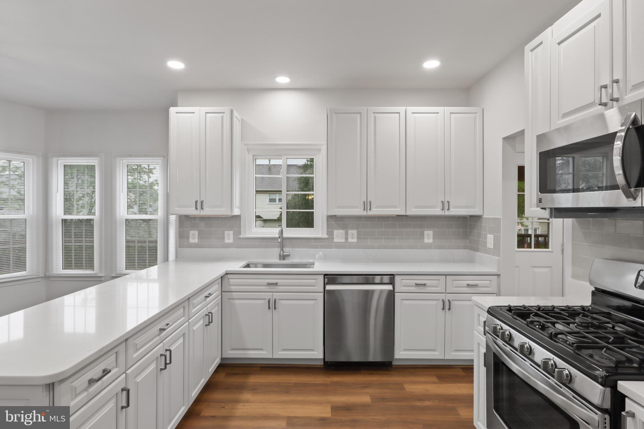 9365 River Crest Road Manassas, VA 20110 - Photo 12 of 62 a kitchen with stainless steel appliances granite countertop a stove a sink dishwasher a refrigerator and white cabinets with wooden floor
