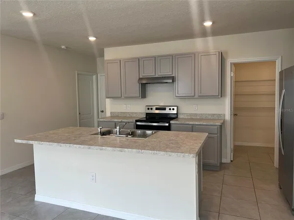 a kitchen with kitchen island granite countertop a sink stove and refrigerator
