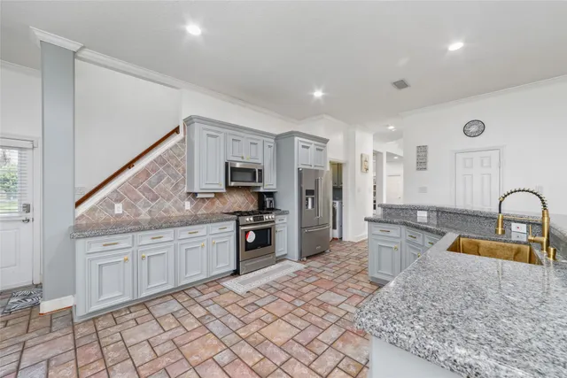 a large kitchen with granite countertop a sink and white cabinets