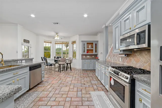 a kitchen with stainless steel appliances granite countertop a stove a sink and a microwave