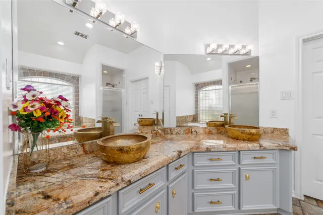 a bathroom with a granite countertop double vanity sink a mirror and shower