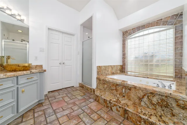 a bathroom with a granite countertop sink and a window