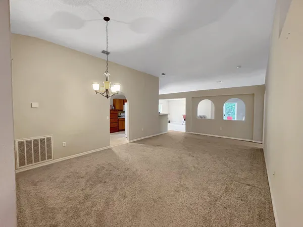a view of a room with a hanging light and kitchen view