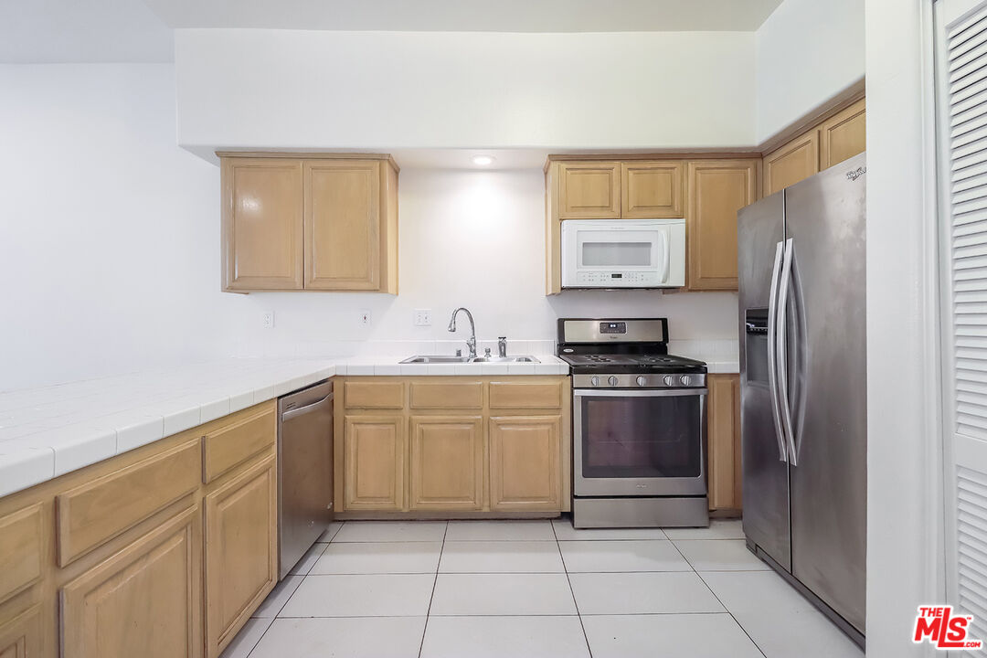 11920 Goshen Avenue, Unit 102 Los Angeles, CA 90049 - Photo 12 of 39 a kitchen with stainless steel appliances granite countertop a refrigerator and a stove top oven