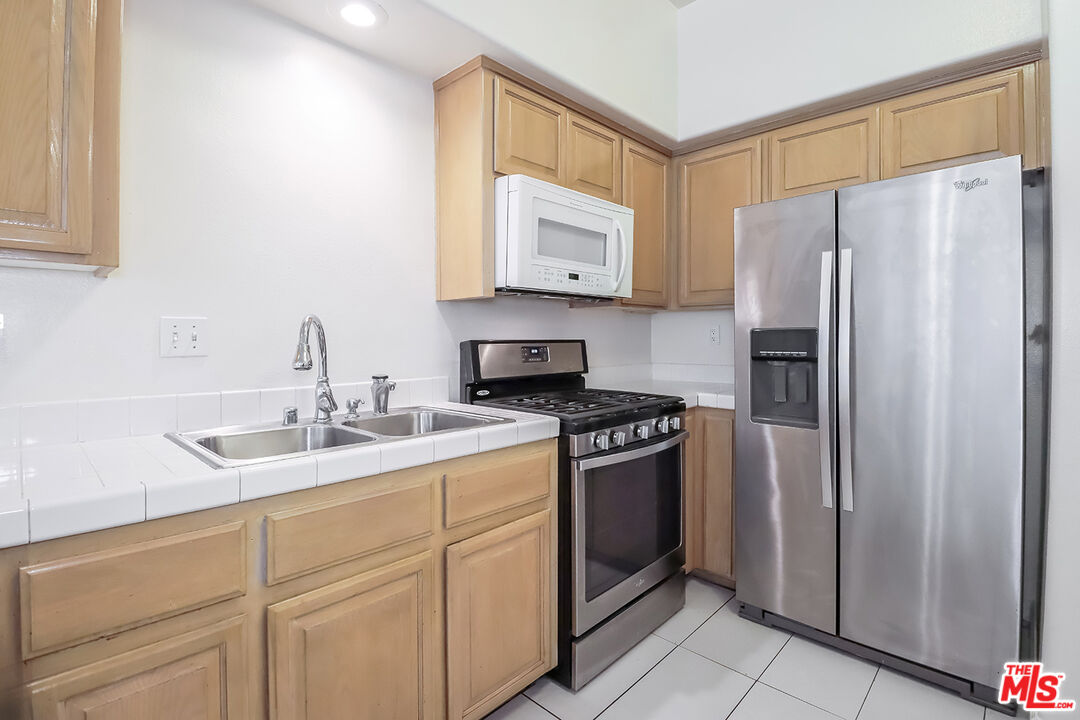 11920 Goshen Avenue, Unit 102 Los Angeles, CA 90049 - Photo 13 of 39 a kitchen with stainless steel appliances granite countertop a refrigerator sink and stove