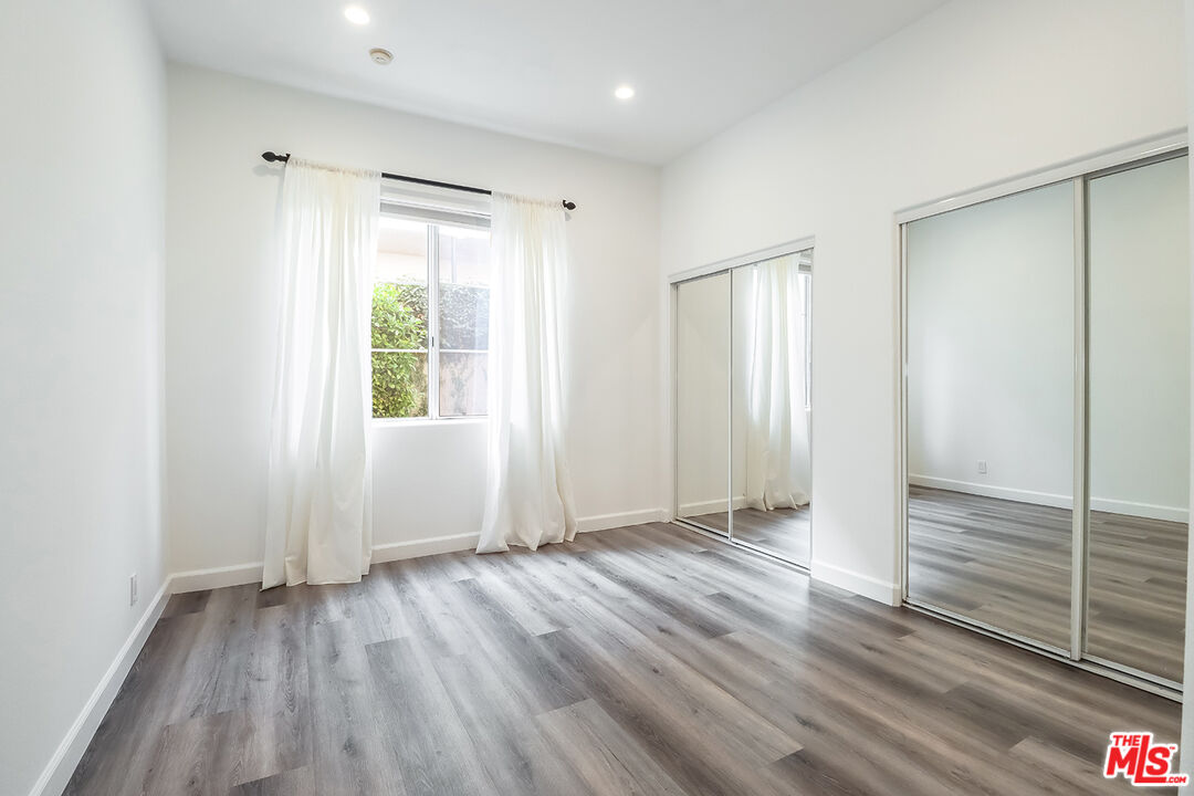 11920 Goshen Avenue, Unit 102 Los Angeles, CA 90049 - Photo 19 of 39 a view of an empty room with wooden floor and a window