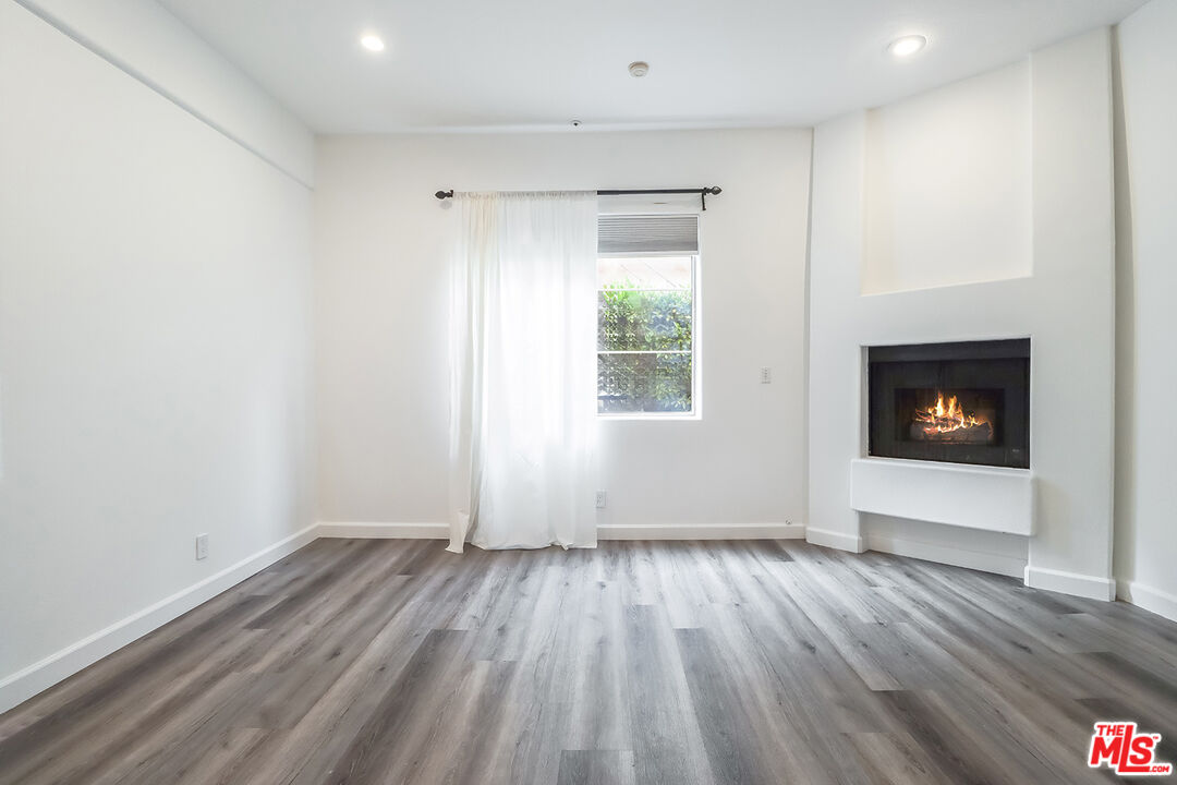 11920 Goshen Avenue, Unit 102 Los Angeles, CA 90049 - Photo 26 of 39 a view of an empty room with wooden floor and a window