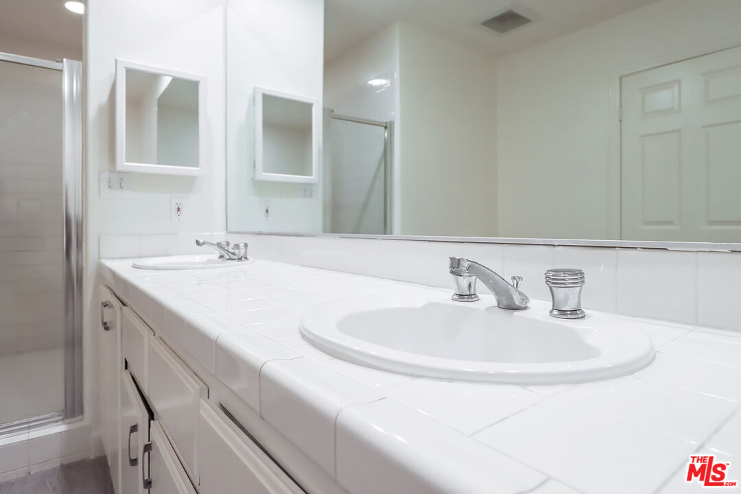 11920 Goshen Avenue, Unit 102 Los Angeles, CA 90049 - Photo 34 of 39 a bathroom with double vanity sinks and a mirror