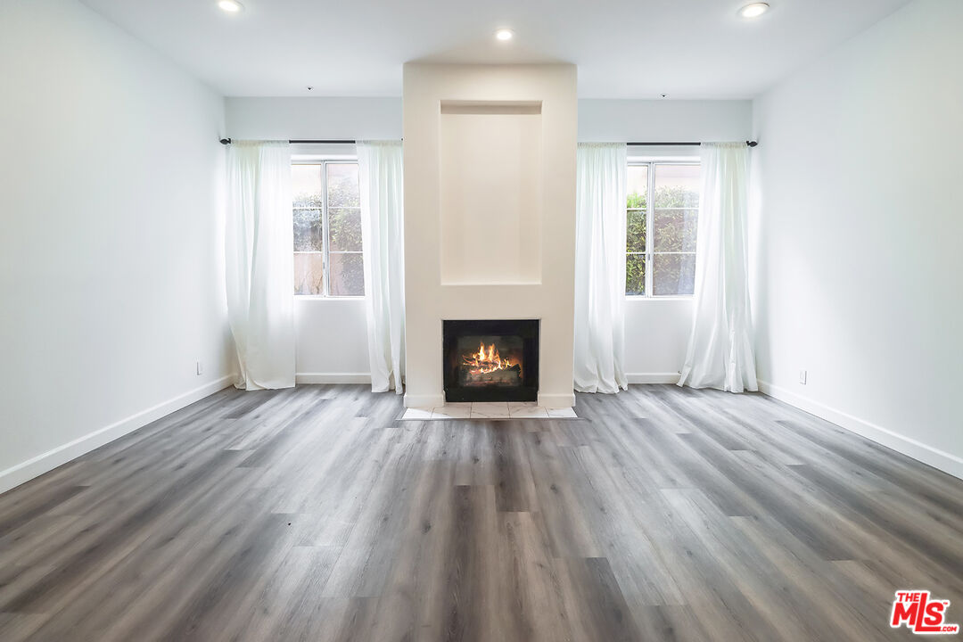11920 Goshen Avenue, Unit 102 Los Angeles, CA 90049 - Photo 5 of 39 a view of an empty room with wooden floor and a window