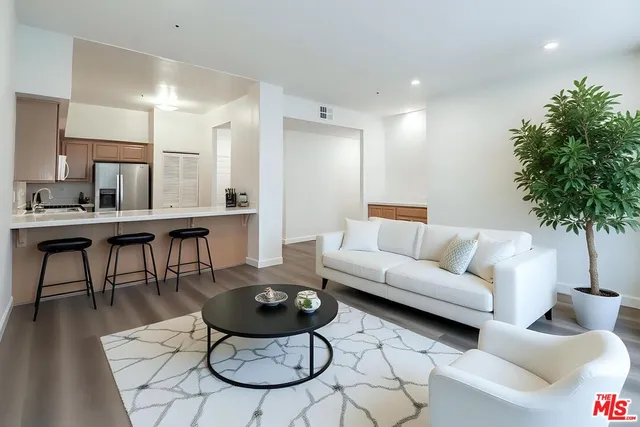 a view of kitchen and empty room with wooden floor