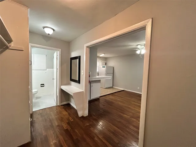 a view of a hallway with wooden floor and a bathroom