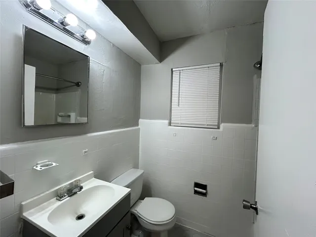 a bathroom with a toilet sink vanity and mirror
