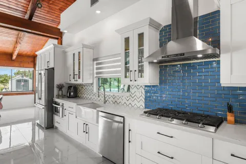 a large kitchen with kitchen island a large counter top space a sink stainless steel appliances and cabinets