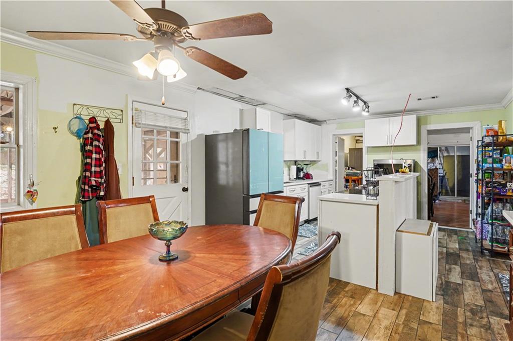 267 Macon Street Monticello, GA 31064 - Photo 11 of 28 a kitchen with stainless steel appliances kitchen island granite countertop a refrigerator a stove top oven a dining table and chairs with wooden floor