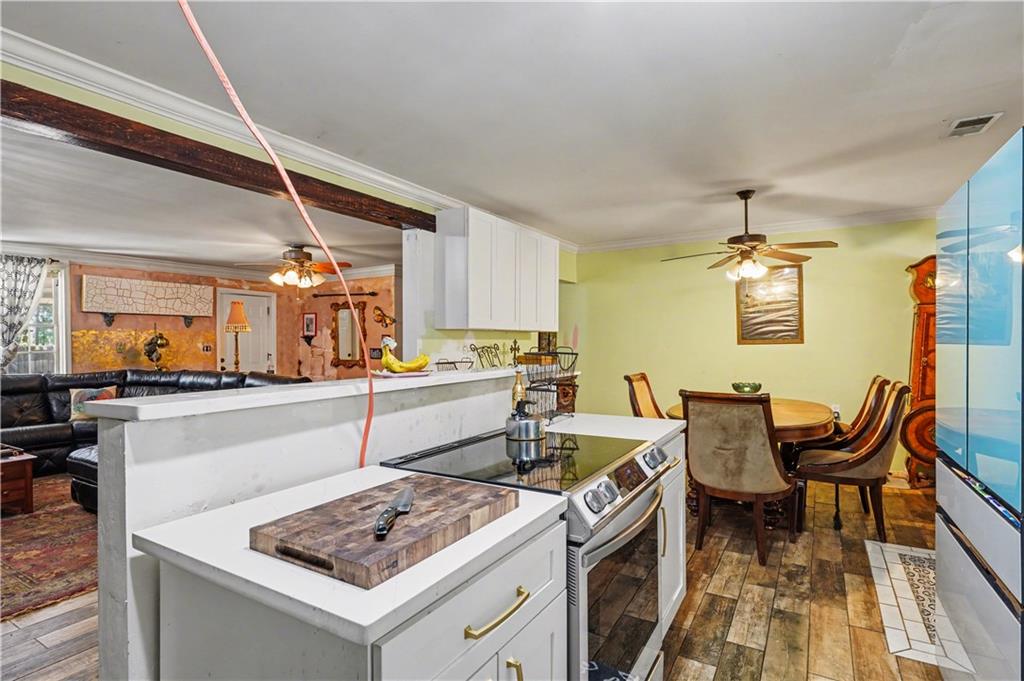 267 Macon Street Monticello, GA 31064 - Photo 6 of 28 a kitchen with a stove a sink dishwasher and white cabinets with wooden floor