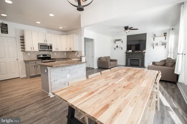 a kitchen with stainless steel appliances granite countertop a refrigerator a stove and a sink with wooden floor