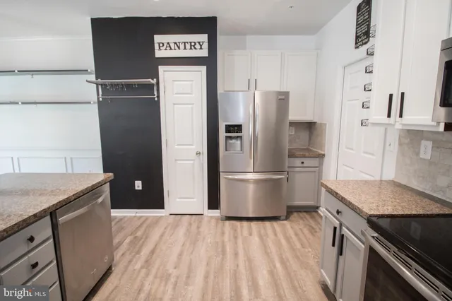 a kitchen with stainless steel appliances granite countertop a sink a stove a microwave a refrigerator a counter space and cabinets