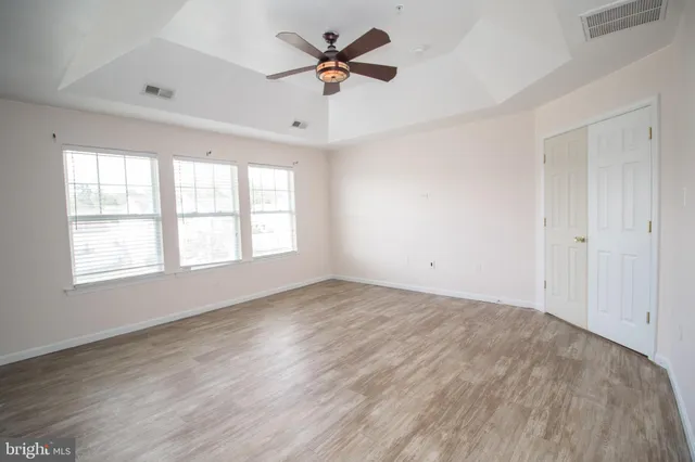 an empty room with wooden floor and chandelier fan