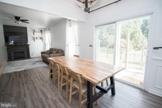 a kitchen with stainless steel appliances kitchen island granite countertop a stove top oven a sink dishwasher and white cabinets with wooden floor