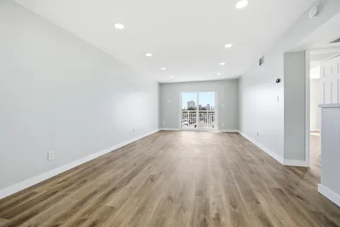 an empty room with wooden floor and windows