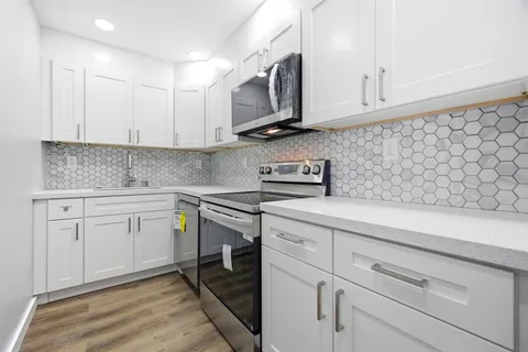 a kitchen with stainless steel appliances granite countertop a sink a stove and cabinets