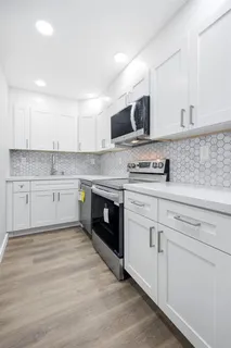 a kitchen with stainless steel appliances granite countertop a stove top oven a sink dishwasher and white cabinets