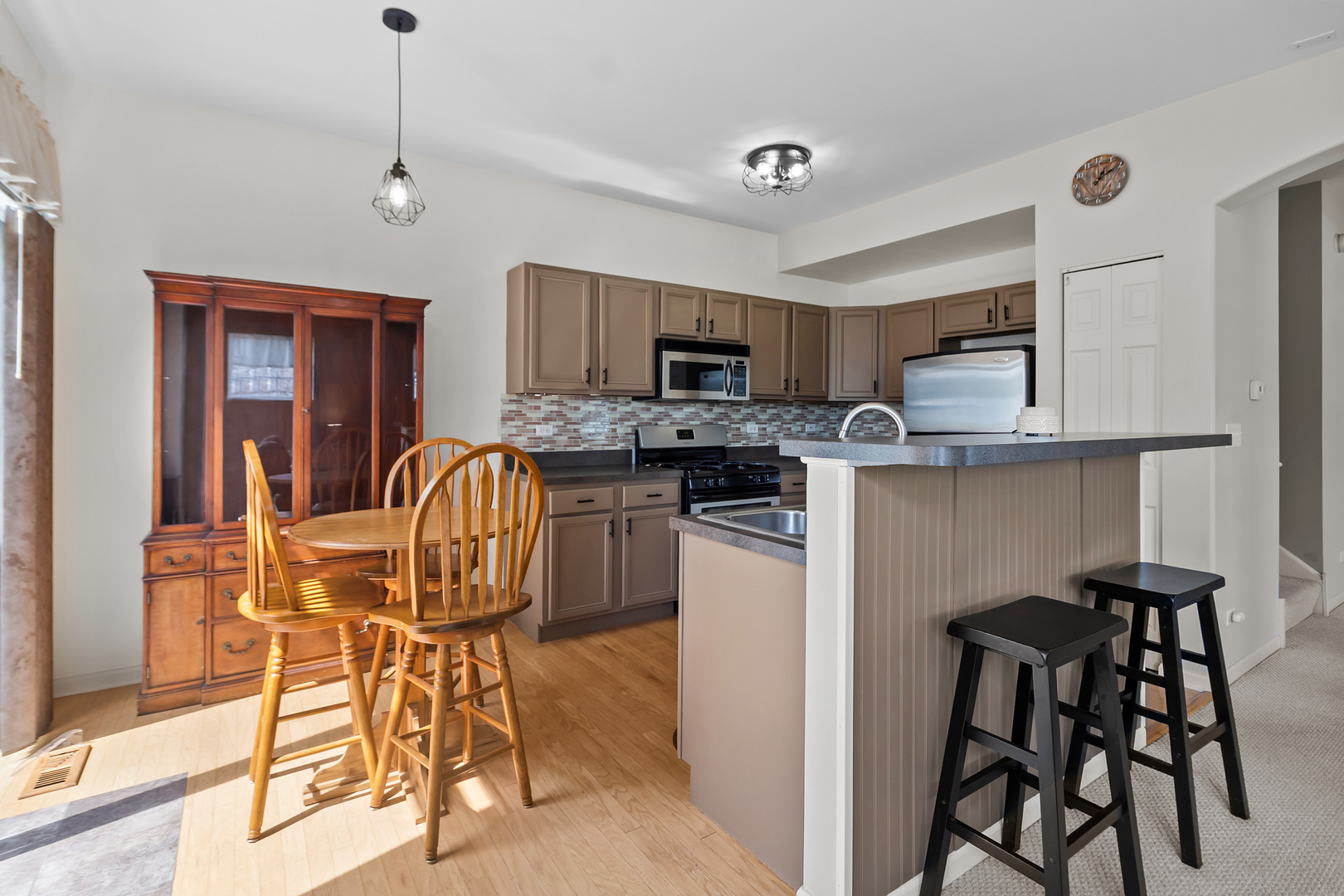 362 Keswick Circle Round Lake, IL 60073 - Photo 9 of 27 a kitchen with stainless steel appliances granite countertop a stove top oven a sink a dining table and chairs with wooden floor