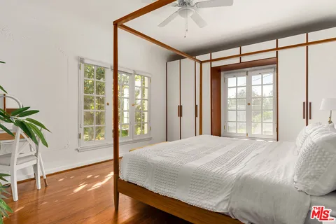 a bedroom with a large bed and a large window with wooden floor