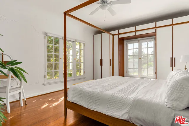 a bedroom with a large bed and a large window with wooden floor