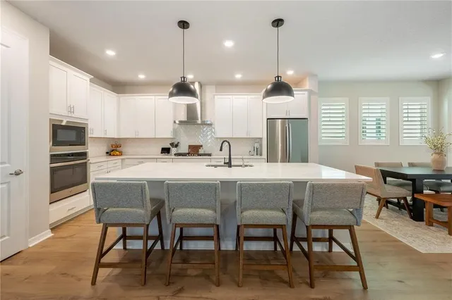 a kitchen with stainless steel appliances granite countertop a sink a stove a refrigerator dining table and chairs