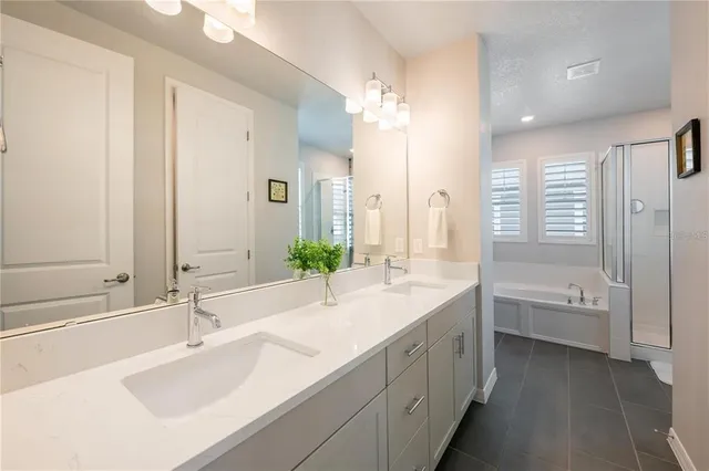 a bathroom with a double vanity sink a mirror and a bathtub