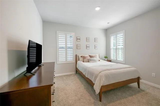 a bedroom with a bed table and a flat screen tv