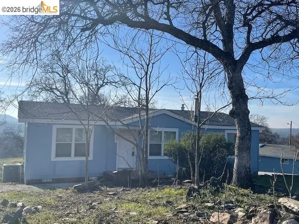 a view of a house with a yard tree and wooden fence