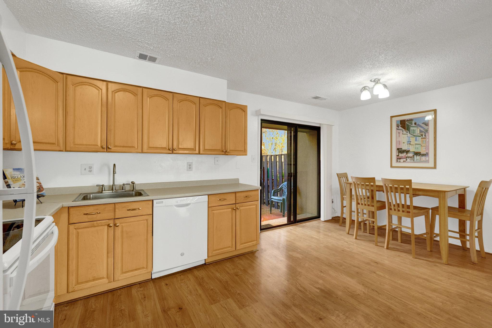 2142 Cartwright Place Reston, VA 20191 - Photo 14 of 46 a kitchen with stainless steel appliances granite countertop a stove top oven a sink dishwasher and white cabinets with wooden floor