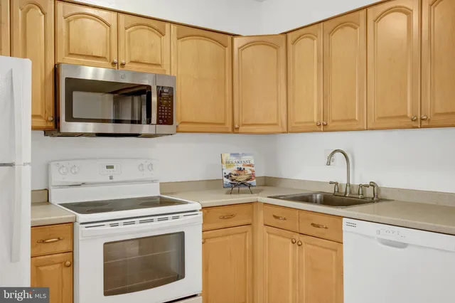 a kitchen with stainless steel appliances granite countertop white cabinets a microwave a sink and a counter space
