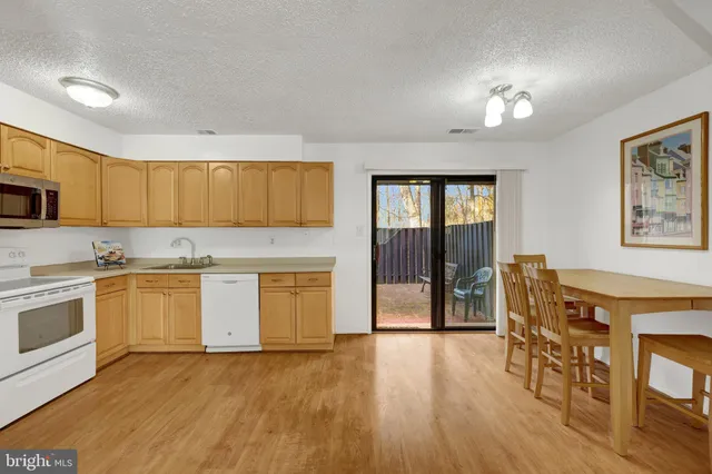 a kitchen with granite countertop a stove top oven a sink dishwasher a dining table and chairs with wooden floor